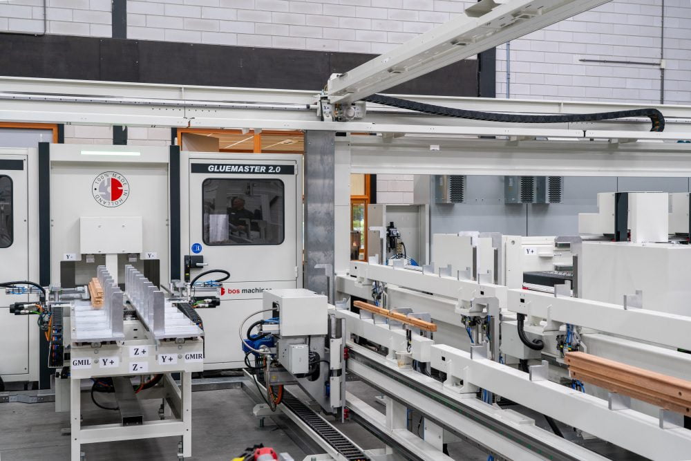 De machine transporteert en plaatst de kozijndelen door een portaalconstructie met twee handelingsunits.