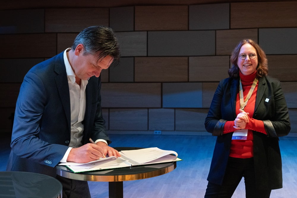 Namens het Ministerie van Binnenlandse Zaken en Koninkrijksrelaties tekende Jan van Beuningen, directeur van de directie Bouwen en Energie. Voorzitter van de Circulaire Geveleconomie Monique Fledderman (VMRBG) Kijkt toe.